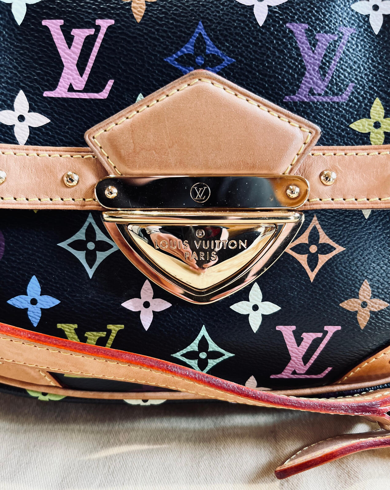The front push-lock closure of the Louis Vuitton Monogram Multicolore Rita Bag
